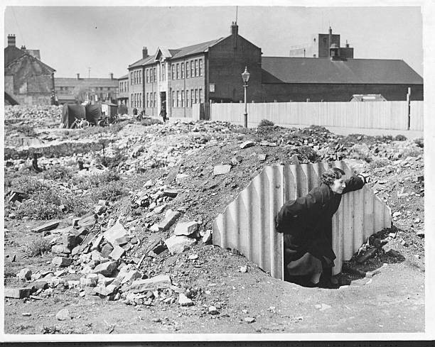 Woman emerges from an air raid shelter built on a demolition site - Old Photo