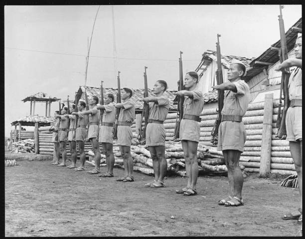 Soldiers stand at attention with their rifles up in the village of- Old Photo