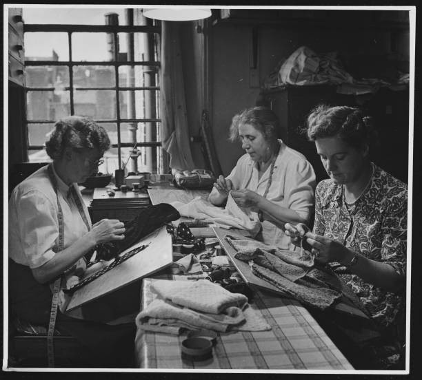 Women sew knitted garments by hand in the London workshop of the M- Old Photo