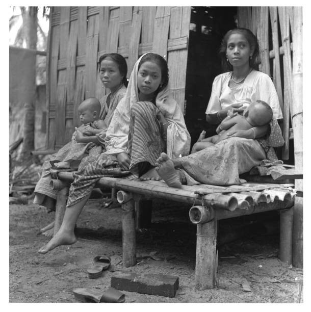 Young mothers nurse their babies at the entrance to a hut Historic Old Photo
