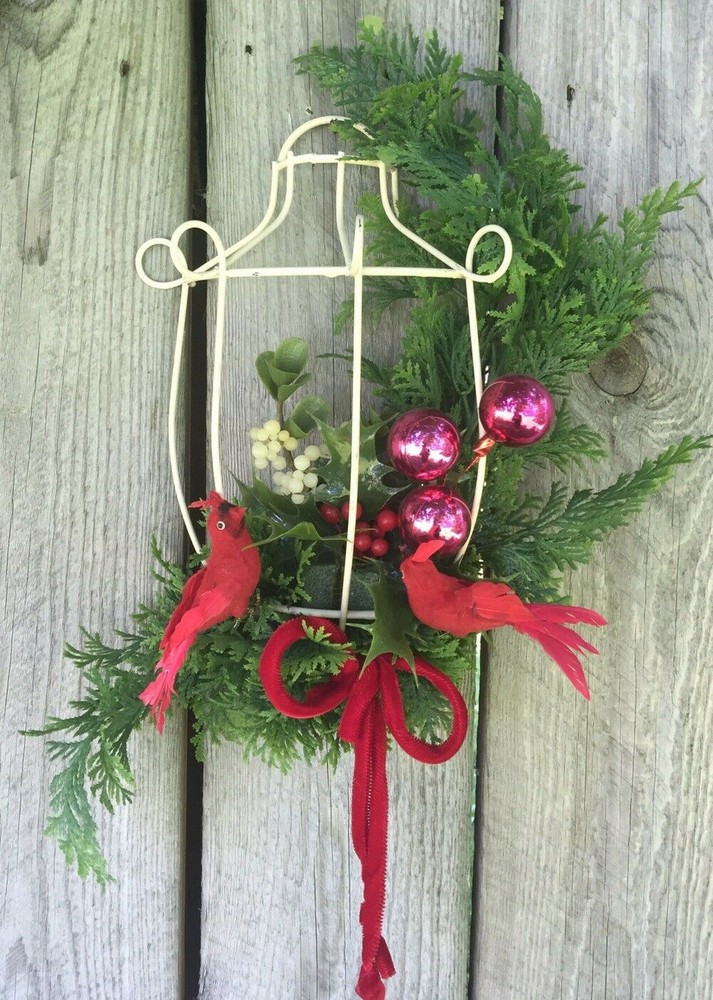 Vintage handmade Christmas decor with cardinals, pine, holly, and berries in bird cage