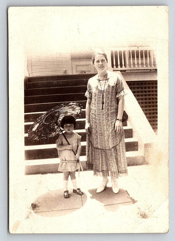 Vintage Mother and Daughter in Dresses with Umbrella by House  