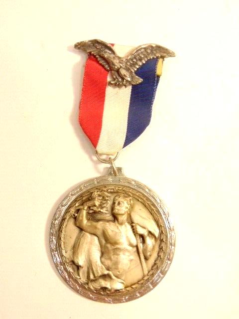 older, large silver colored medal showing hero holding laurel wreath