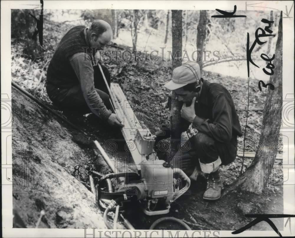 1955 Press Photo Men measure rock's radiation levels with Geiger Counter