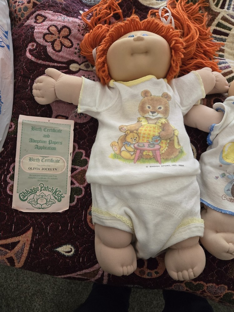 Cabbage Patch Kids Doll has orange hair and blue eyes. Baby has blue eyes