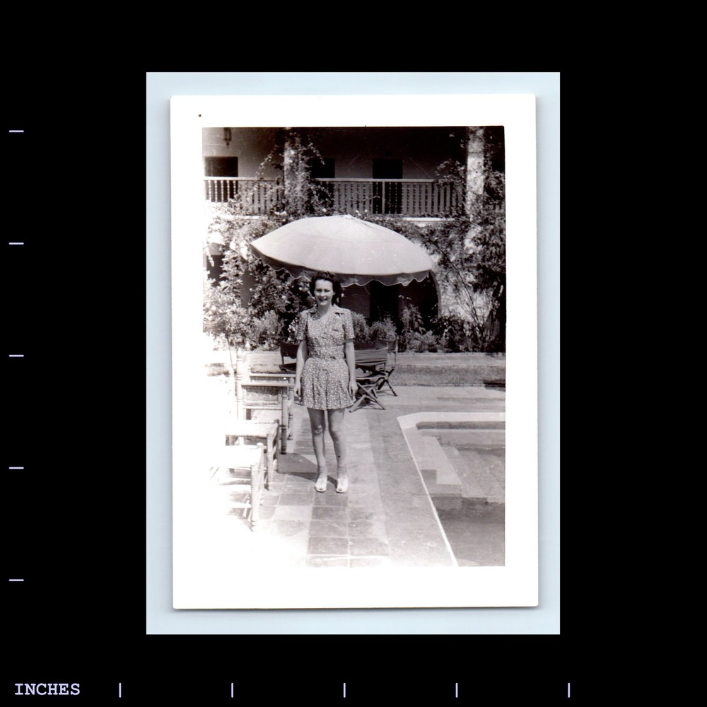 Vintage Black and White Photo of a Woman Relaxing Under an Umbrella by a Serene Poolside – Timeless Elegance and Nostalgic Charm