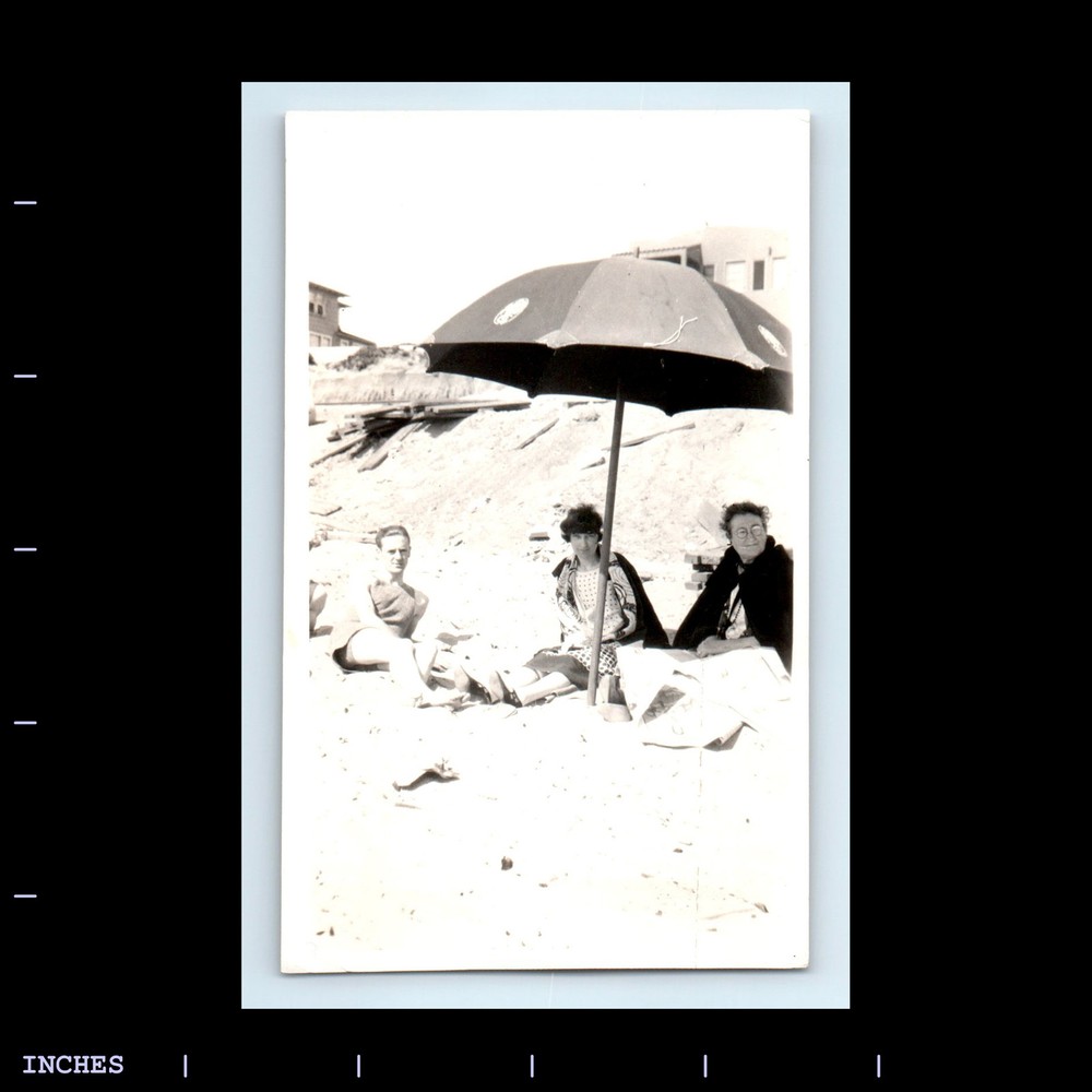 Vintage Beach Scene with Sunbathing Couple Under Umbrella